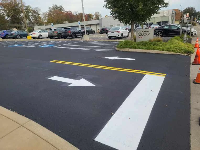 Newly sealed and striped asphalt parking lot with white arrows and yellow lines