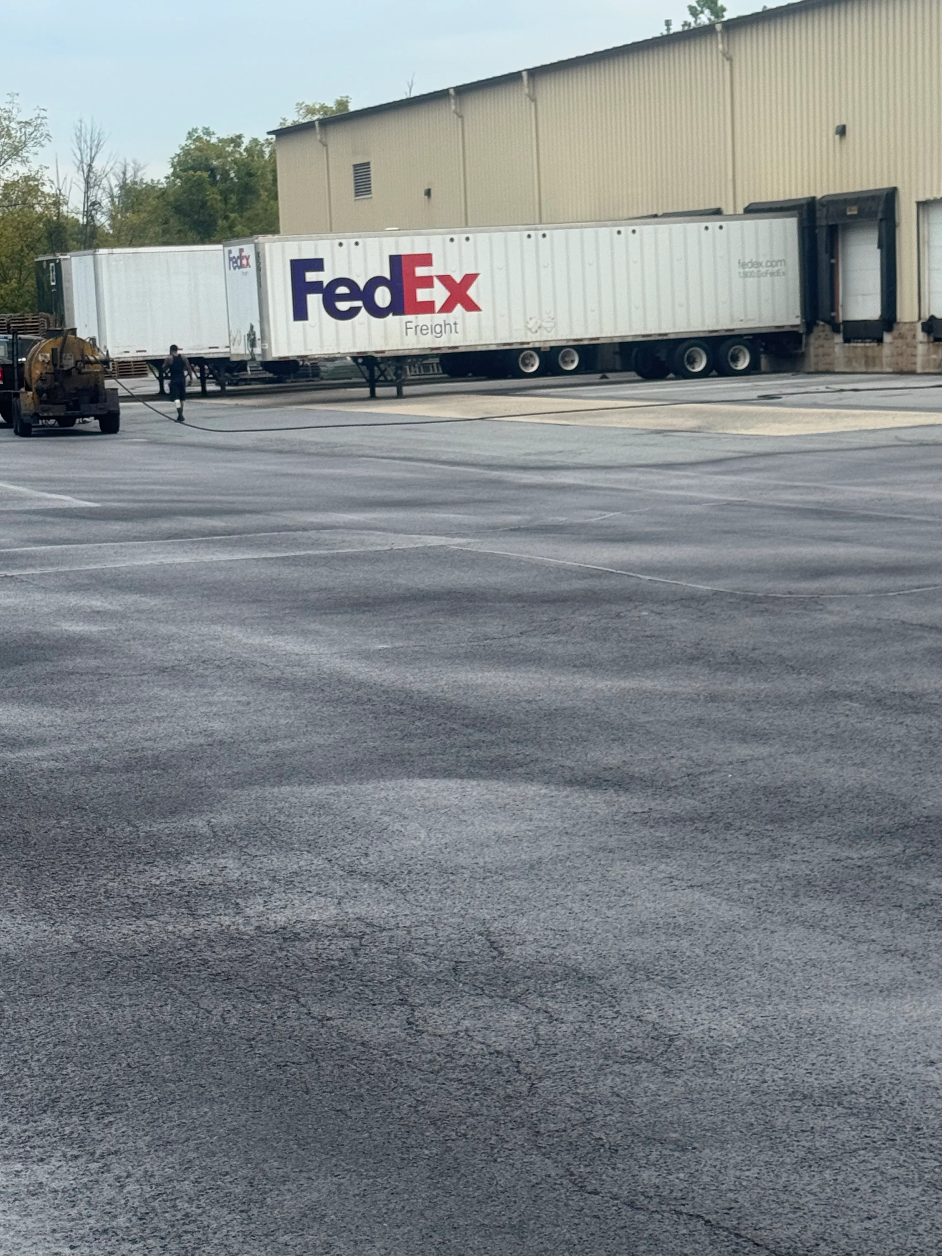 Sealed asphalt parking lot with FedEx Freight trailer and industrial building