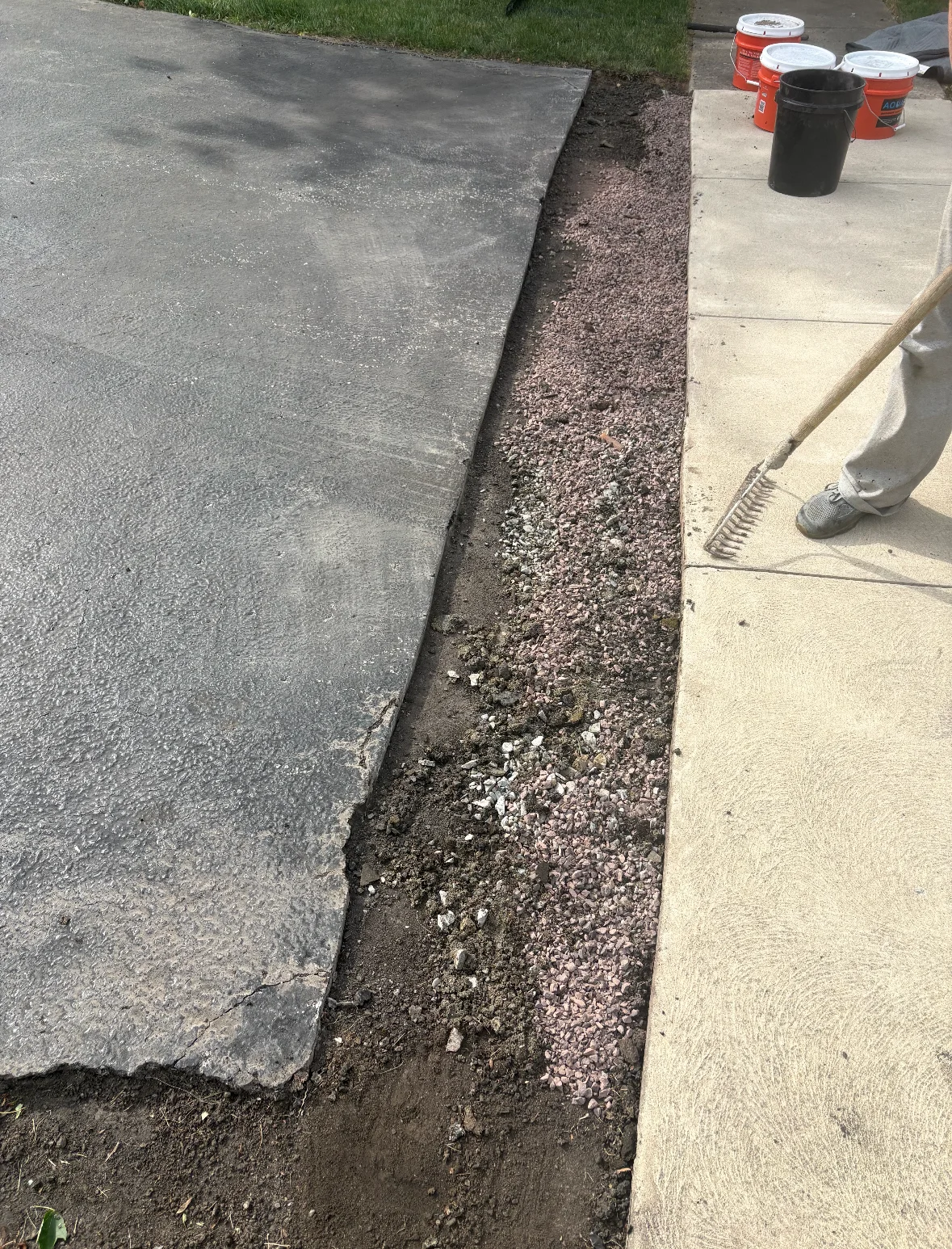 Asphalt patch repair with fresh gravel base along driveway edge