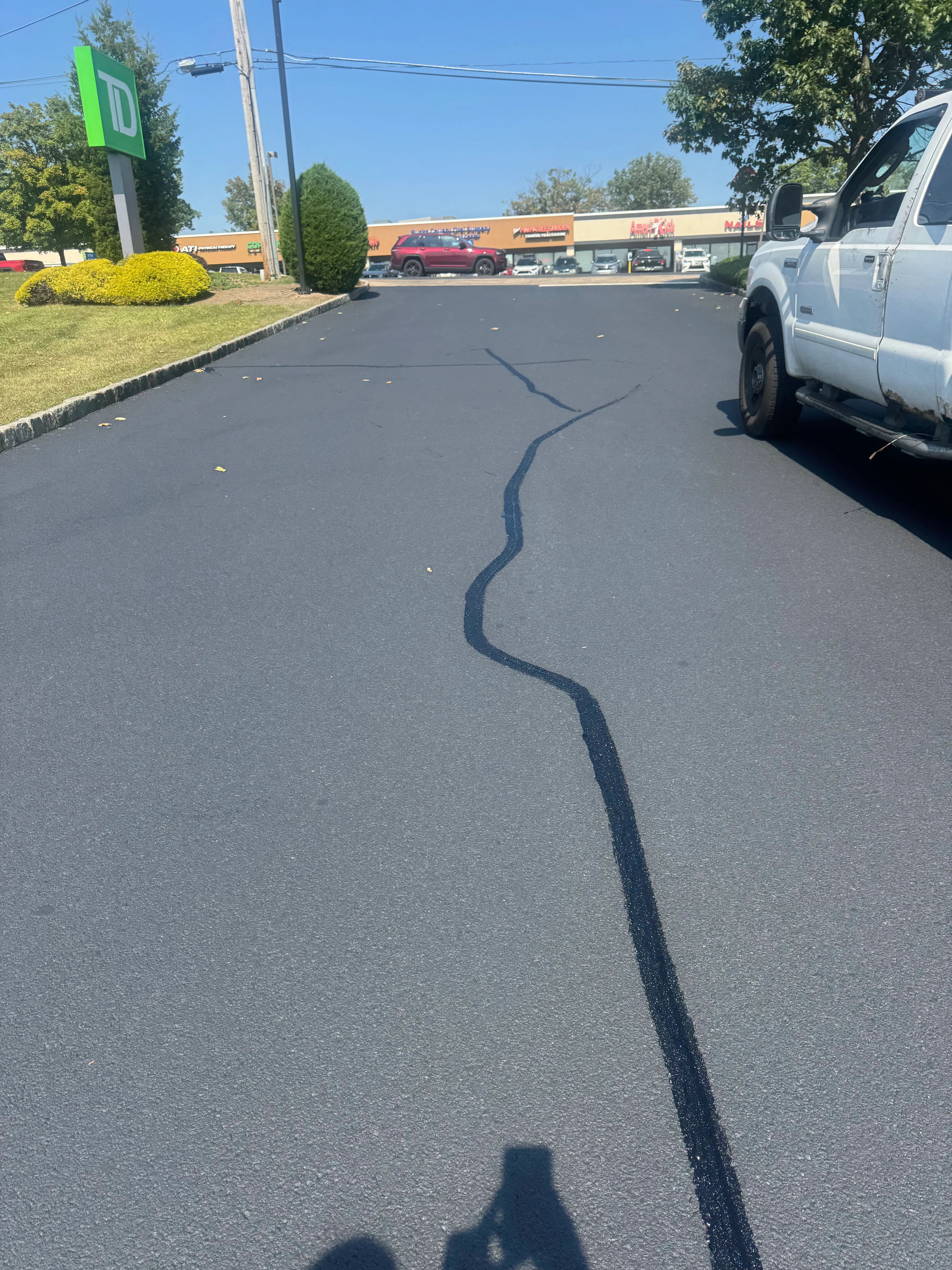 Sealed asphalt crack running across commercial parking lot surface