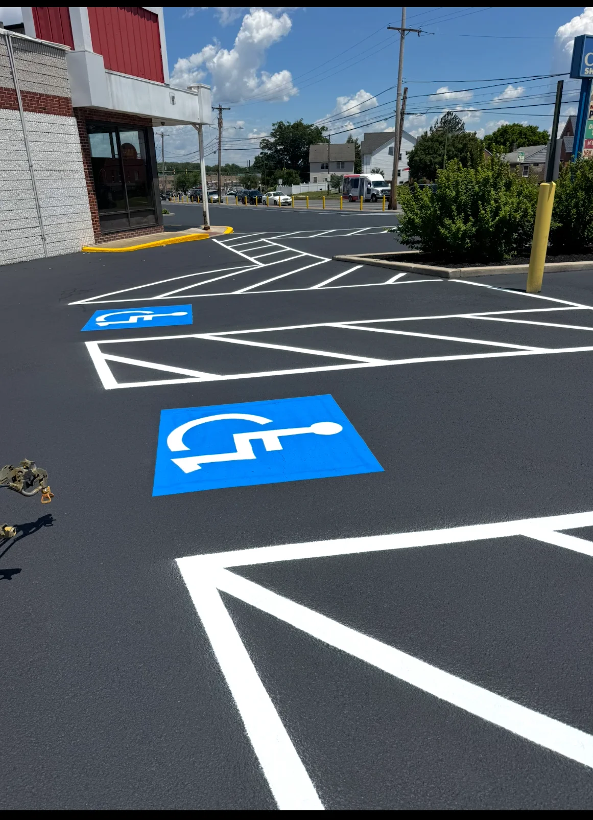 Commercial parking lot with white line striping and blue ADA handicap parking symbols on dark asphalt