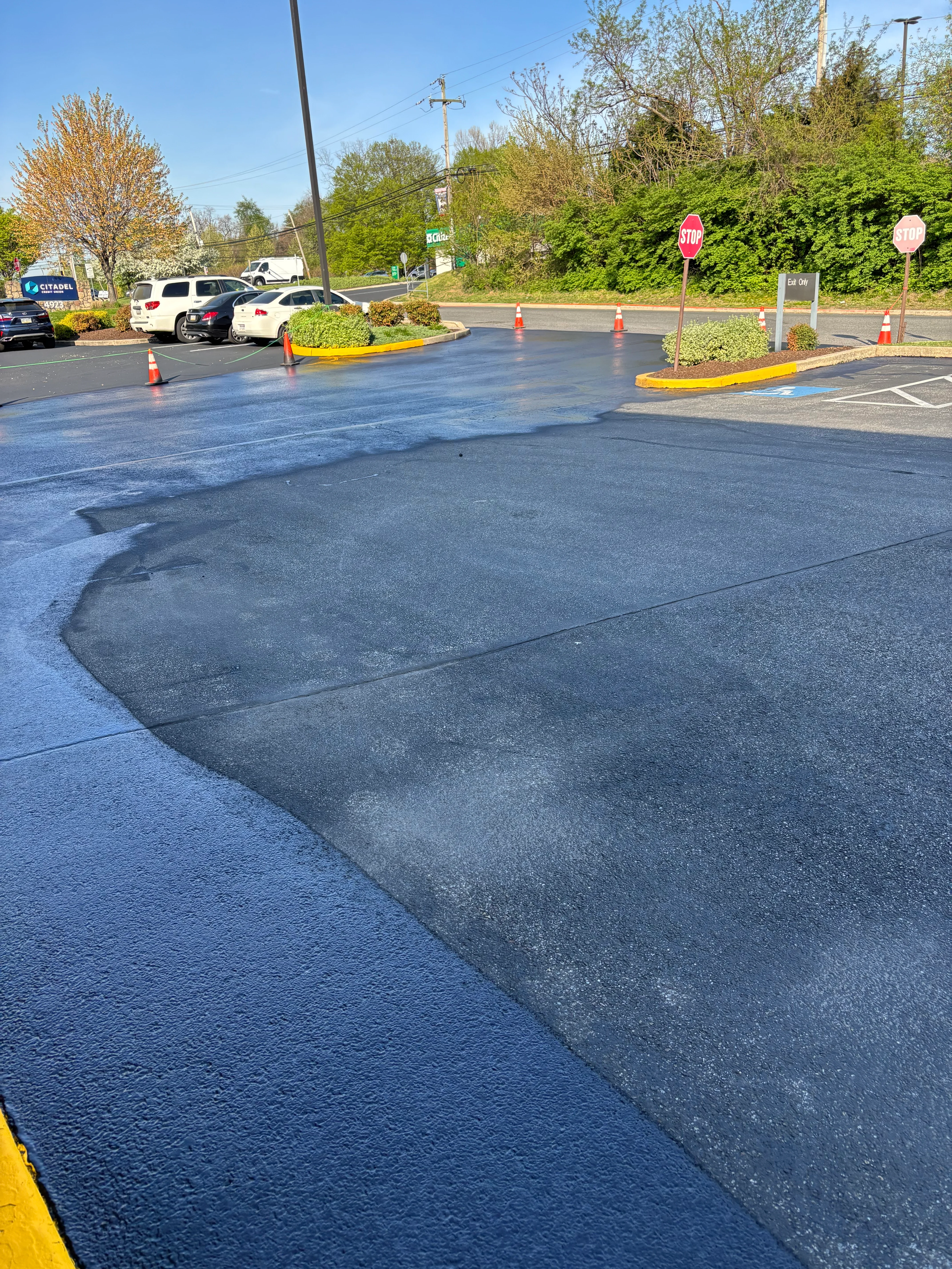 Freshly sealcoated parking lot with yellow curb striping and traffic cones