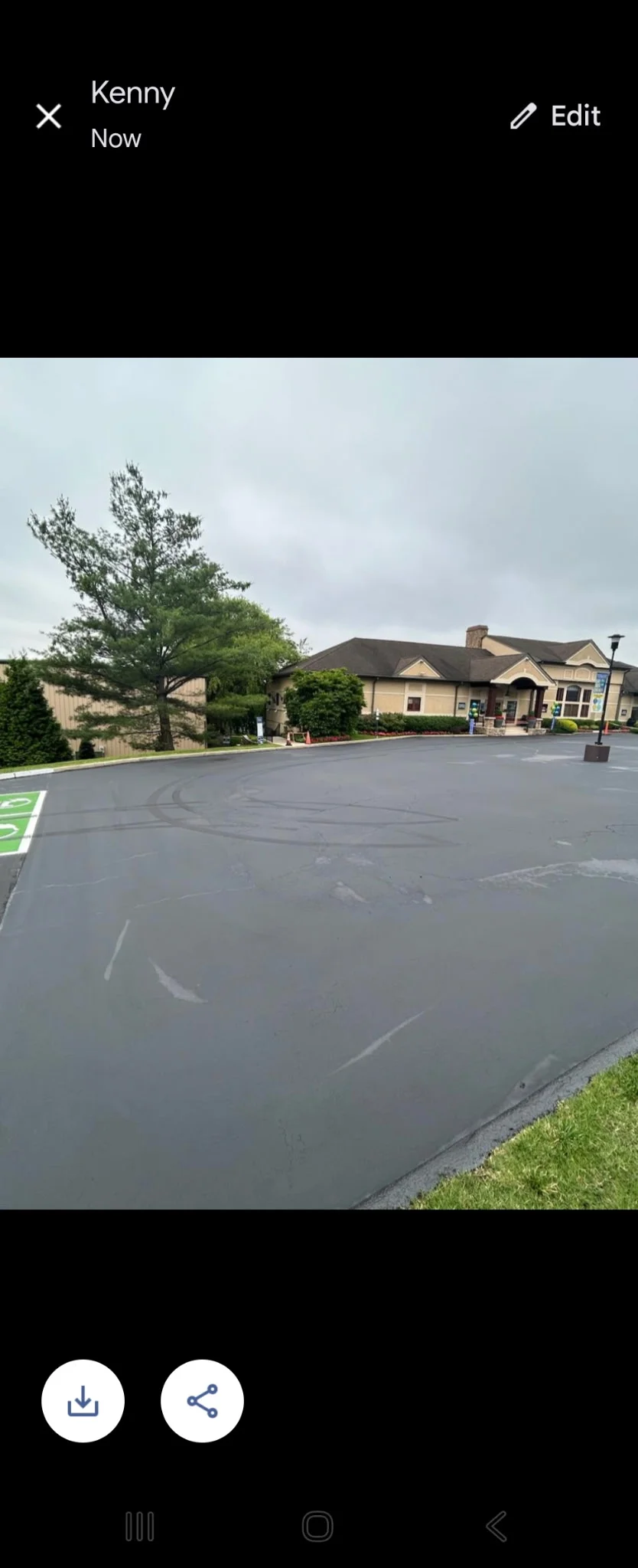 Freshly sealcoated commercial parking lot with clear markings and landscaping
