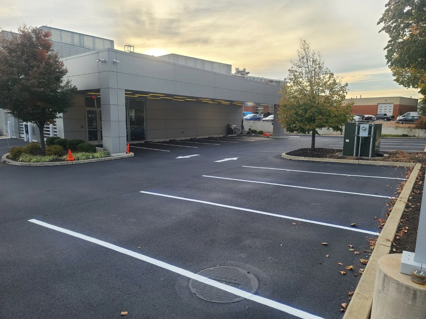 Newly sealed and striped commercial parking lot with white line markings and modern building entrance